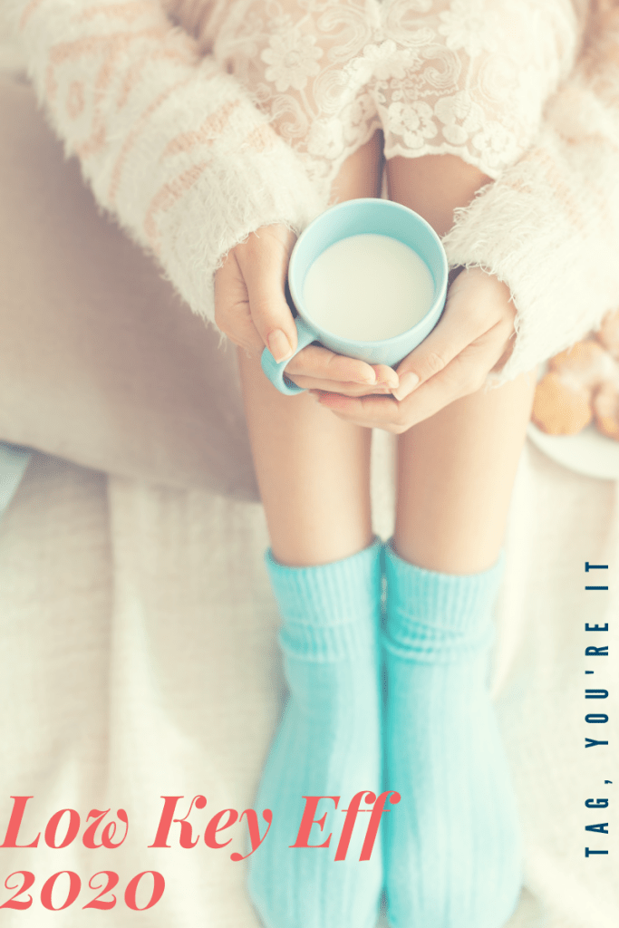 Image is of a white woman holding what honestly looks like milk in a light blue coffee cup with her socks in the picture (you can't see her face); words on image read tag you're it and low key eff 2020
